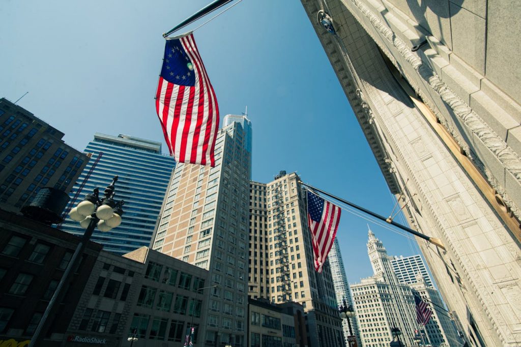 Low angle view of Chicago skyscrapers with American flags, representing urban America.