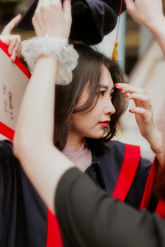 A happy graduate wearing a cap and gown celebrates her achievement.